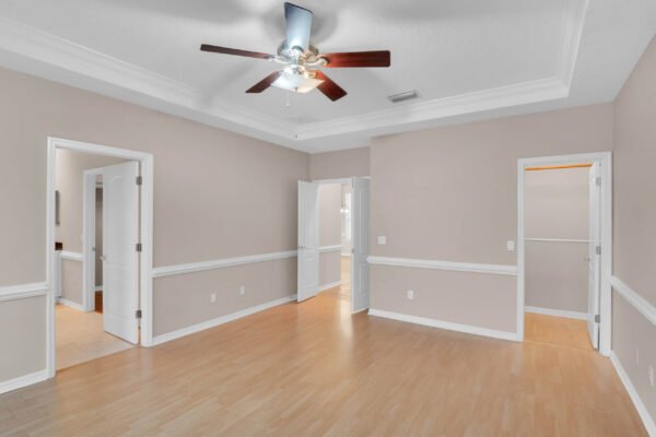 Spacious interior of a Windermere home featuring hardwood floors, crown molding, and ceiling fan, showcasing multiple doorways leading to various rooms.