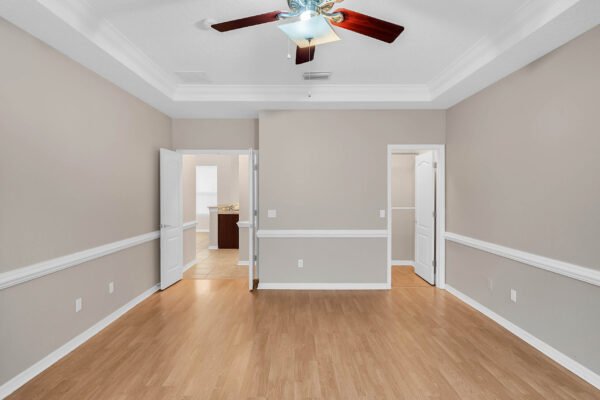 Spacious interior of a Windermere home featuring hardwood flooring, crown molding, and open doorway leading to kitchen, ideal for showcasing 4-bedroom layout.