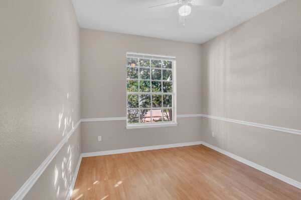 Bright interior room with hardwood flooring, large window allowing natural light, and ceiling fan, suitable for home office or bedroom in Windermere property listing.