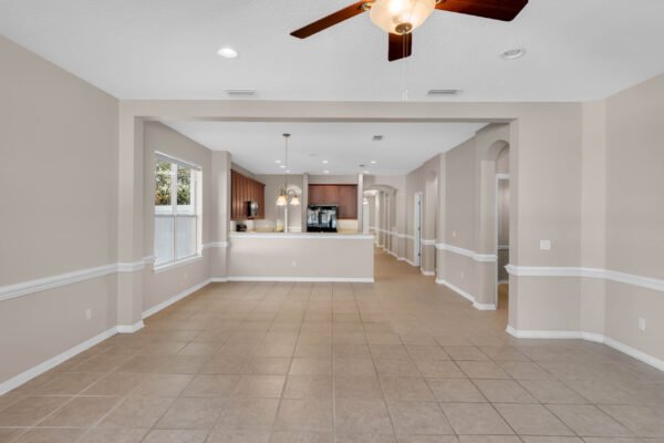 Open concept living space with tile flooring, neutral walls, and a ceiling fan, showcasing the kitchen area with dark cabinetry and modern appliances, ideal for the Windermere real estate market.