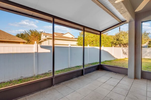 Screened patio area with tiled floor, overlooking a fenced yard and neighboring homes in Windermere, Florida, ideal for outdoor living and entertaining.