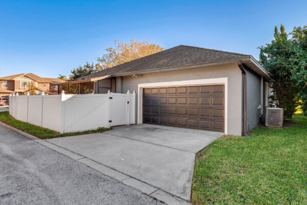 Corner lot home in Windermere, FL with fenced yard, garage, and driveway, showcasing a well-maintained exterior.