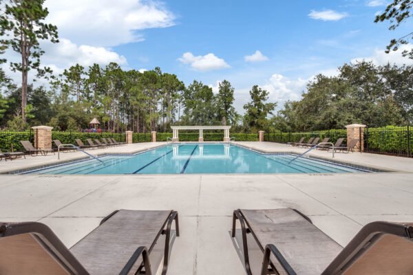 Swimming pool in Windermere community surrounded by lounge chairs and lush greenery, highlighting outdoor amenities ideal for relaxation and recreation.