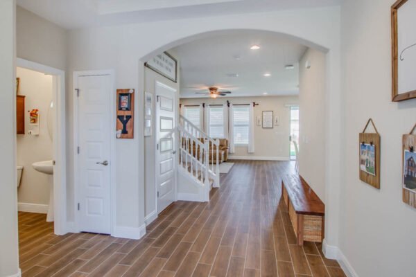 Modern entryway of a home featuring an open layout, wooden tile flooring, staircase leading to the upper level, and natural light from windows, highlighting a welcoming atmosphere in Winter Garden, FL.