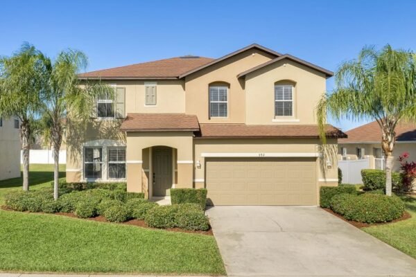 Two-story residential home at 592 First Cape Coral Dr, Winter Garden, FL, featuring a landscaped front yard with palm trees, a two-car garage, and a painted exterior, ideal for potential buyers seeking affordable real estate in a gated community.