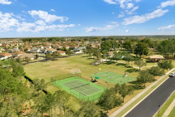 Aerial view of a community park in Winter Garden, FL, featuring tennis courts, basketball courts, a playground, and expansive green space, surrounded by residential homes.