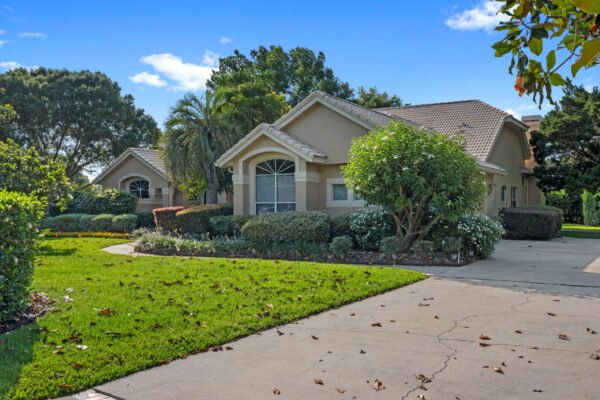 Stunning custom home exterior at 11359 Willow Gardens Drive in Windermere, FL, featuring lush landscaping, large windows, and a welcoming driveway, showcasing Florida living in a serene neighborhood.