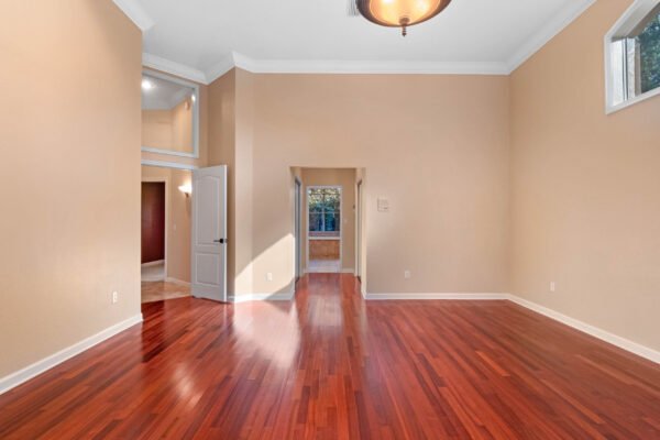 Spacious interior of a custom home in Windermere, featuring polished hardwood floors, high ceilings, and natural light streaming through large windows, showcasing an open layout leading to outdoor living spaces.