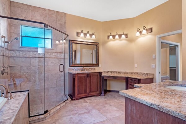 Luxurious bathroom featuring a glass-enclosed shower, granite countertops, elegant lighting, and a spacious vanity area, showcasing modern design elements in a Windermere home.