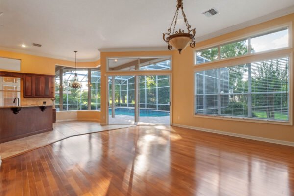 Spacious living area with hardwood floors, large windows, and views of the pool area, showcasing the elegant design of a custom home in Windermere, Florida.