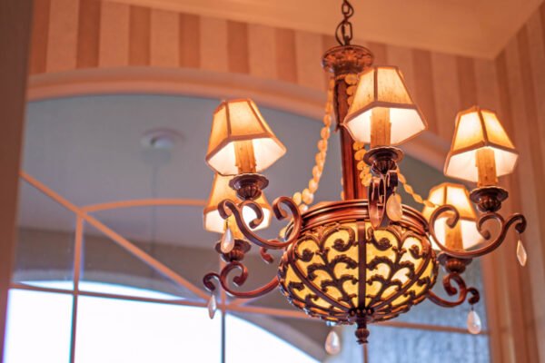 Chandelier with ornate design and warm lighting, illuminating the elegant interior of a custom home in Windermere, showcasing luxury and style.