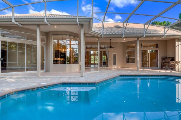 Luxury home with pool and screened lanai in Windermere, showcasing large windows and spacious outdoor living area, ideal for Florida living.