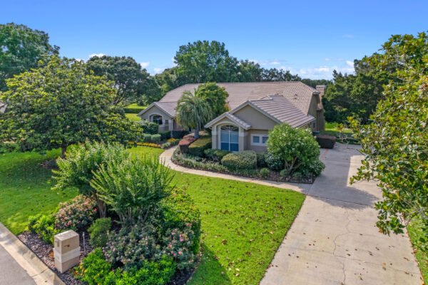 Stunning custom home exterior on Willow Gardens Drive in Windermere, surrounded by lush landscaping, mature trees, and manicured lawn, showcasing Florida living and privacy.