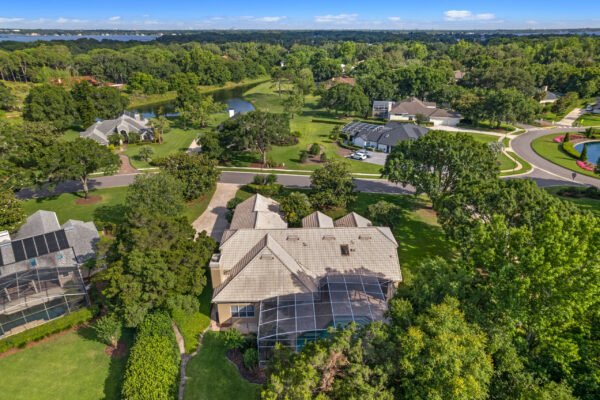 Aerial view of a stunning custom home at 11359 Willow Gardens Drive, Windermere, FL, surrounded by lush greenery, manicured lawns, and scenic views, showcasing the property's expansive lot and proximity to the peaceful Willows of Lake Rhea community.