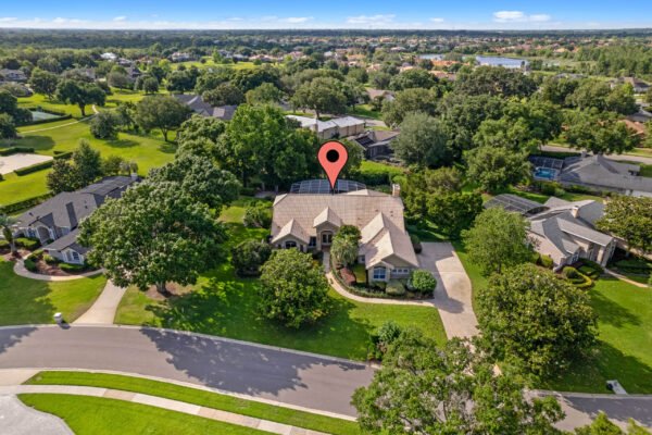 Aerial view of 11359 Willow Gardens Drive in Windermere, FL, showcasing a spacious custom home surrounded by lush greenery and a well-maintained landscape, highlighting its prime location in the desirable Willows of Lake Rhea community.