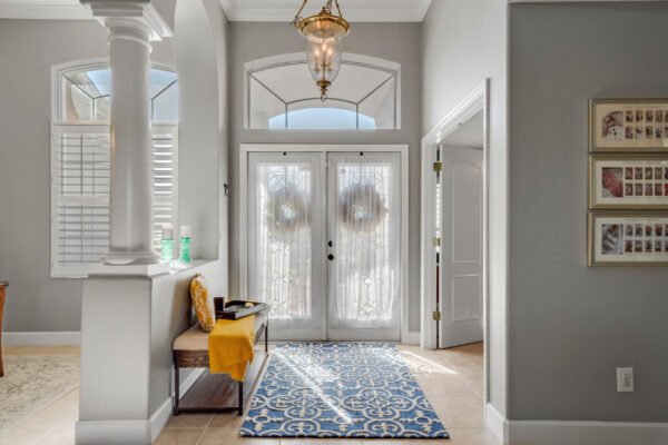 Elegant entryway of a home at 13915 Zephermoor Lane, featuring double glass doors with wreaths, a blue patterned rug, and a welcoming atmosphere, reflecting the spacious and meticulously cared-for design of the property.
