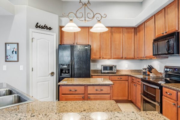 Modern kitchen with wooden cabinets, granite countertops, stainless steel appliances, and pendant lighting, showcasing a spacious layout ideal for cooking and entertaining.