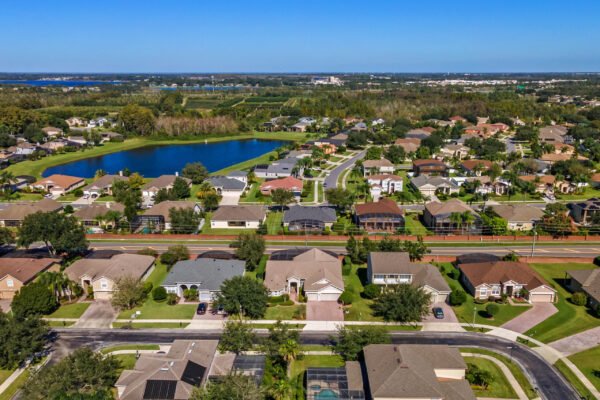 Aerial view of residential neighborhood in Winter Garden, Florida, showcasing homes, well-maintained lawns, winding streets, and a large pond, emphasizing the community's appeal and proximity to nature.