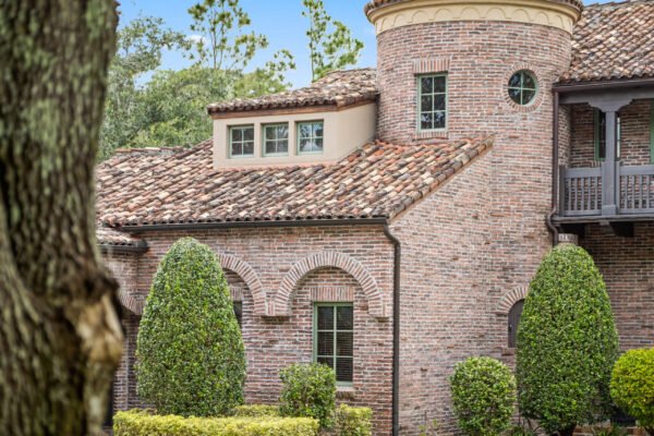 Luxury home exterior featuring brick architecture, terracotta roof, and manicured landscaping at 11019 Bridge House Road, Windermere, FL.
