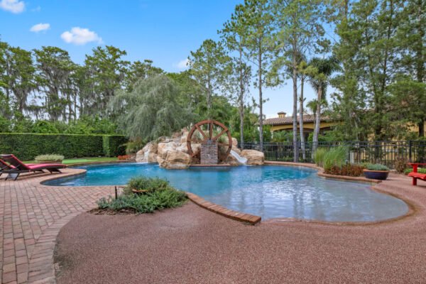 Luxury lakefront pool area with water feature and lush landscaping at 11019 Bridge House Road, Windermere, FL.