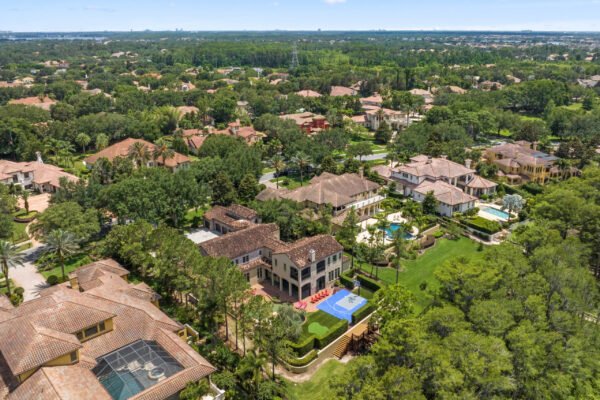 Aerial view of luxury home at 11019 Bridge House Road, Windermere, FL, showcasing spacious grounds, swimming pool, and surrounding upscale neighborhood.