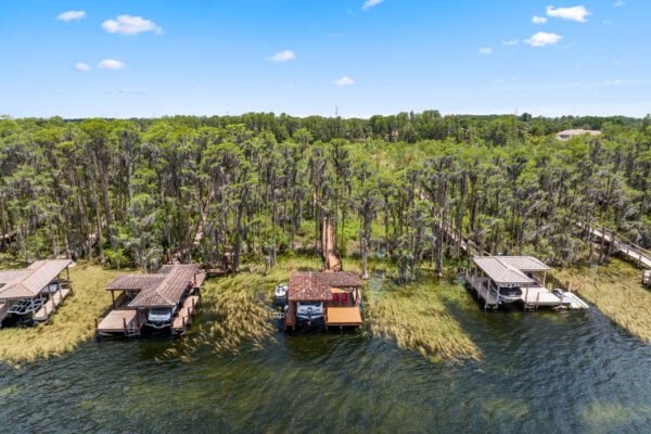 Lakefront view of private boat docks surrounded by lush greenery and water, showcasing the serene outdoor lifestyle near 11019 Bridge House Road in Windermere, FL.