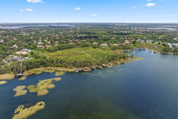 Aerial view of the lakefront property at 11019 Bridge House Road in Windermere, showcasing lush greenery, private docks, and the scenic Lake Butler, highlighting the luxurious lifestyle and exclusivity of the Reserve at Lake Butler Sound.