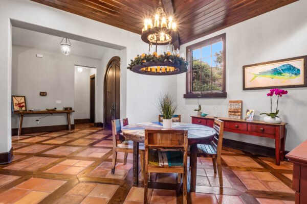 Dining area featuring a round table with colorful chairs, rustic chandelier, and terracotta tile flooring, showcasing a blend of elegance and warmth in the luxury home at 11019 Bridge House Road, Windermere, FL.