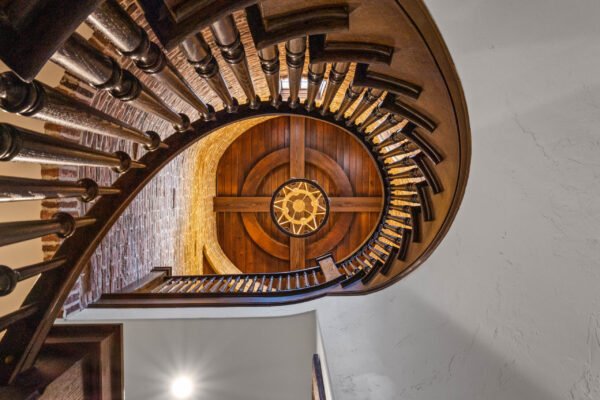 Spiral wooden staircase with intricate railing and decorative circular ceiling design in luxury home at 11019 Bridge House Road, Windermere, FL.