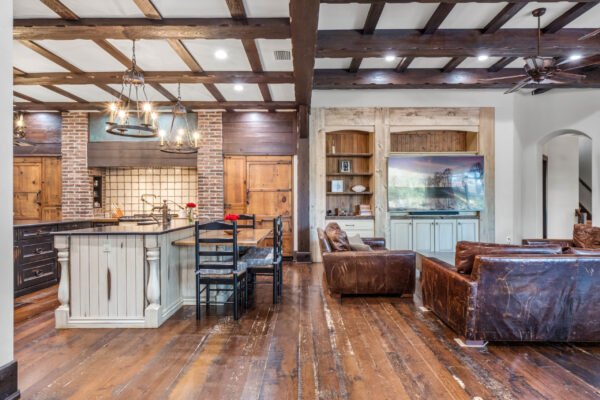 Spacious kitchen and living area featuring rustic wooden beams, modern appliances, and cozy seating, showcasing the luxurious interior of the home at 11019 Bridge House Road in Windermere, FL.