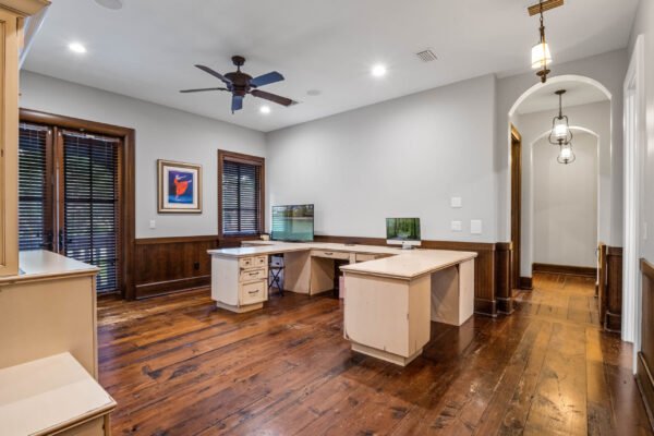 Home office with modern desk setup, wooden flooring, large windows with blinds, and decorative artwork, showcasing a luxurious interior design in a Windermere estate.