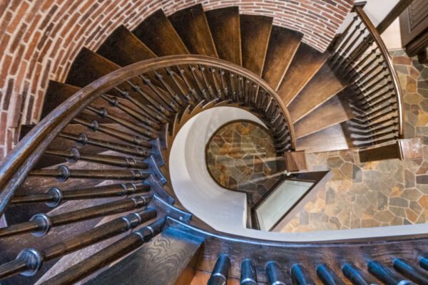Spiral staircase with dark wooden steps and black railings, showcasing elegant craftsmanship in a luxury home setting.