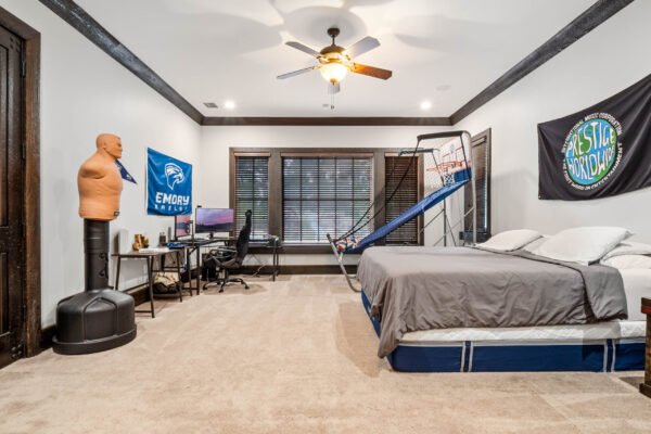 Spacious bedroom featuring a basketball hoop, desk setup, and Emory University flag, designed for comfort and leisure in a luxury home.