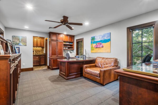 Luxurious home office featuring rich wooden cabinetry, a comfortable leather chair, and vibrant artwork, designed for a sophisticated lifestyle in a high-end Windermere estate.
