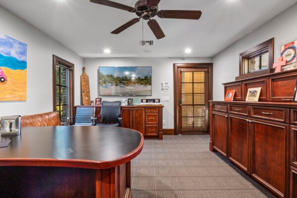 Luxury home office with dark wood furniture, leather seating, artwork, and large window showcasing natural light, reflecting the upscale design of the property at 11019 Bridge House Road in Windermere, FL.