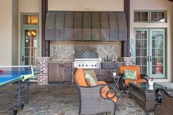 Luxury outdoor kitchen and living space with stone flooring, built-in grill, and comfortable seating at 11019 Bridge House Road, Windermere, FL.