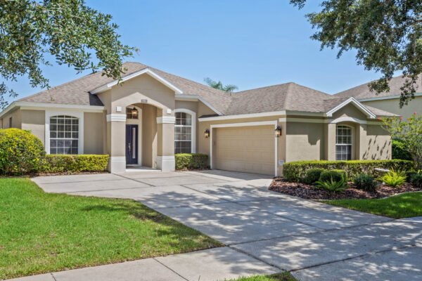 Single-story home at 15061 Spinnaker Cove Lane, Winter Garden, FL, featuring a manicured lawn, two-car garage, and welcoming entryway, ideal for family living.