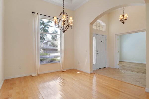 Bright entryway of a remodeled one-story home at 15061 Spinnaker Cove Lane, featuring hardwood floors, large windows, decorative chandelier, and access to a welcoming foyer and adjacent rooms.
