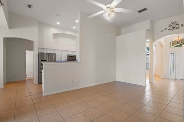 Spacious interior of a remodeled one-story home at 15061 Spinnaker Cove Lane, featuring a tile floor, ceiling fan, and open layout connecting kitchen and living areas, highlighting the modern design ideal for family living.