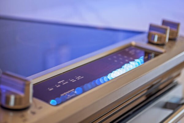 Control panel of a modern kitchen appliance with illuminated buttons and digital display, showcasing advanced features for a remodeled home.