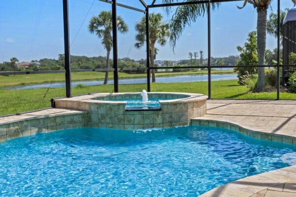 Heated pool and spa with waterfall feature, surrounded by screened enclosure, overlooking lush green landscape and tranquil water views in Winter Garden, FL.