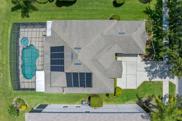 Aerial view of 15061 Spinnaker Cove Lane, showcasing a one-story home with a screened pool, solar panels, and landscaped yard in Winter Garden, FL.