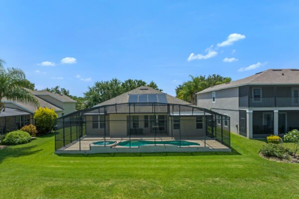 Automated pool home with screened enclosure, solar panels, and landscaped backyard in Winter Garden, Florida, showcasing spacious outdoor area and neighboring homes.