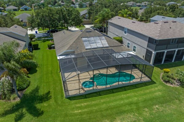 Aerial view of a one-story home in Winter Garden, FL, featuring a screened pool and spa area, surrounded by lush green grass and landscaping, showcasing the outdoor living space in a quiet cul-de-sac setting.