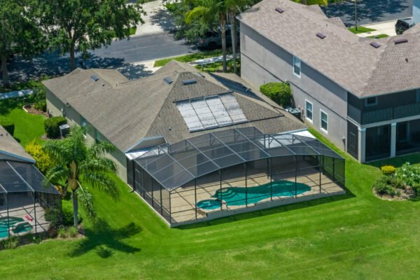Aerial view of a one-story home at 15061 Spinnaker Cove Lane, Winter Garden, FL, featuring a screened-in pool area, landscaped yard, and nearby palm trees, showcasing the property's outdoor amenities in a quiet cul-de-sac setting.