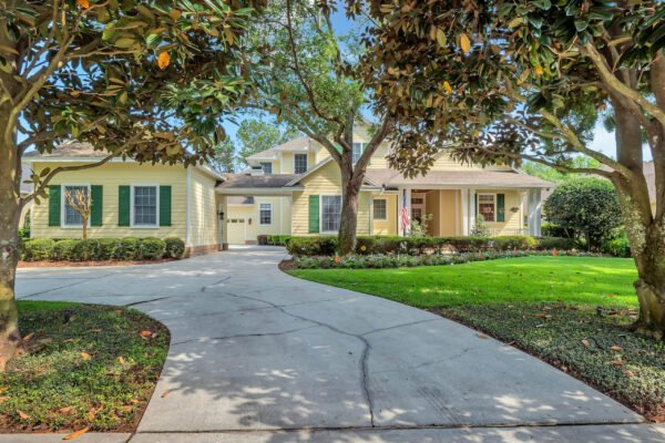 Custom-built estate at 6264 Blakeford Drive, Windermere, FL, featuring a charming exterior with yellow siding, green shutters, and a landscaped yard, set on a spacious driveway surrounded by mature trees.