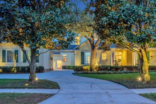 Custom-built estate at 6264 Blakeford Drive in Windermere, FL, featuring a well-lit driveway, manicured landscaping, and elegant architectural design, set against a twilight backdrop.