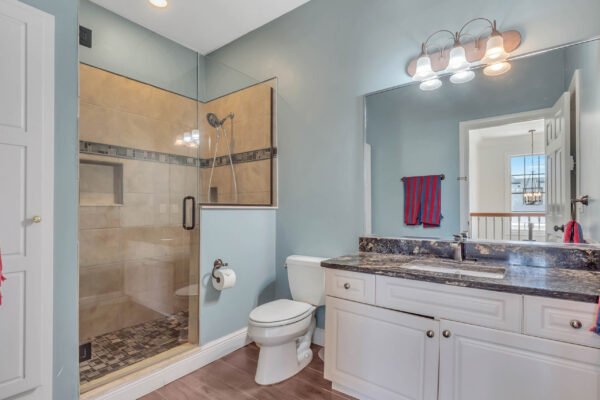 Bathroom featuring a glass shower, modern fixtures, granite countertop, and natural light from adjacent window, showcasing stylish design elements in a Windermere estate home.