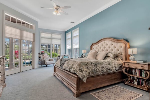 Luxurious bedroom in custom-built estate at 6264 Blakeford Drive, featuring a king-sized bed, elegant decor, and large windows with views of the landscaped backyard and pool, ideal for Windermere real estate market showcase.