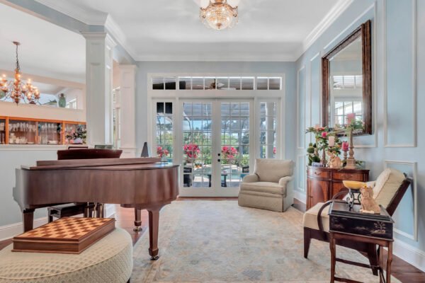 Elegant interior of a custom-built estate in Windermere, featuring a grand piano, plush seating, and large windows with views of landscaped grounds and the golf course, highlighting luxury living and design.